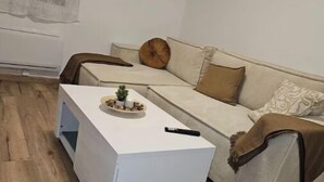 A living room with a white sofa, a white coffee table, and a wooden floor.