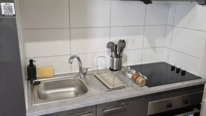 Et køkken med en stålvask, en indbygget komfur og en mikroovn.
