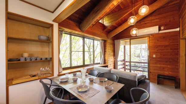 L’intérieur est en bois et comprend une table à manger pour quatre personnes, entourée de chaises. On y trouve des étagères remplies d’assiettes et de verres, ainsi qu’une grande fenêtre qui laisse entrer la lumière naturelle.