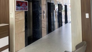 A hotel lobby with marble flooring, a reception desk, and a waiting area with a chair.