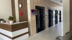 A hotel reception area with a reception desk, a clock, a red decorative item, and a signboard.