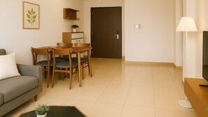A living room with a sofa, a dining table with chairs, a small potted plant, and a lamp.