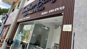 Une devanture de magasin avec une enseigne indiquant « Teacher Bong Hair-Nail & Cafe » et un numéro de téléphone.