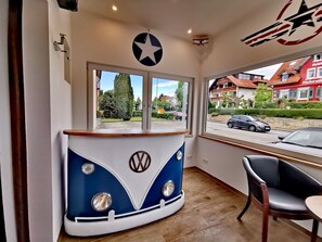 Une pièce avec un comptoir incurvé aux couleurs bleu et blanc, un luminaire en forme d’étoile et une vue sur une rue bordée d’immeubles.