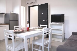 A compact living space with a kitchenette, a dining area, and a seating area with a television.