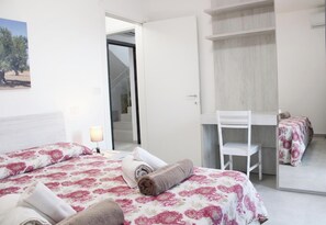 A hotel room with two beds, a desk, a chair, and a wardrobe.