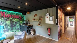 Una habitación acogedora con un letrero de neón, un escritorio, una silla, una mesita y un extintor.