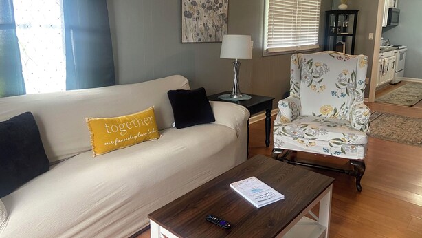 A living room with a sofa, armchair, coffee table, lamp, and artwork on the wall.