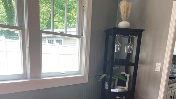 A cozy room with a bench, a tall cabinet, and a window with a view of trees. - Hillside Hideaway (Weber City)