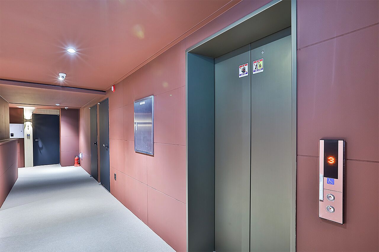 An elevator with a digital display, emergency stop button, and accessibility sign.