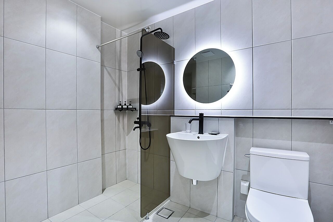 Et moderne badeværelse med et glasvægshus, en hvid vask og et toilet.