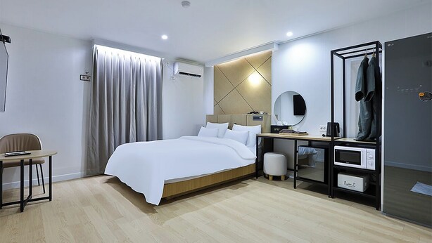 A modern hotel room with a bed, a desk with a mirror, a chair, and a wardrobe. - Brown Dot Hotel Gumi Okgye Branch (Gumi)