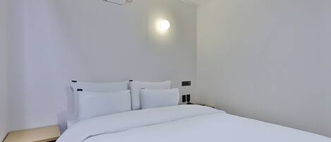 Quarto de hotel com cama, mesa de cabeceira e ar condicionado fixado na parede.