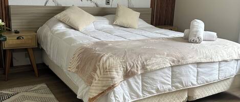 A modern hotel room with a large bed, a wooden headboard, a marble wall, and a wooden floor.