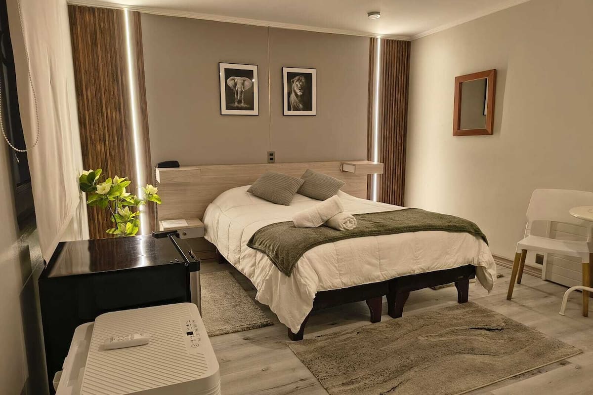 A modern bedroom with a bed, bedside tables, a mirror, and framed pictures on the wall.