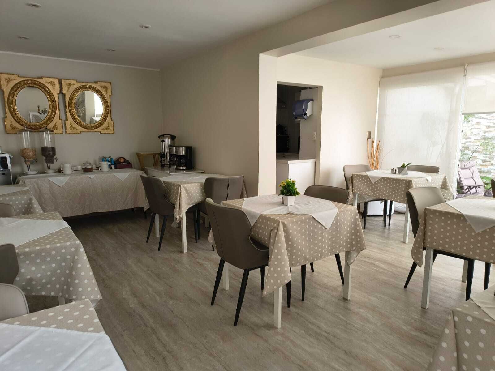 Un espace repas comprenant plusieurs tables, des chaises et une machine à café.
