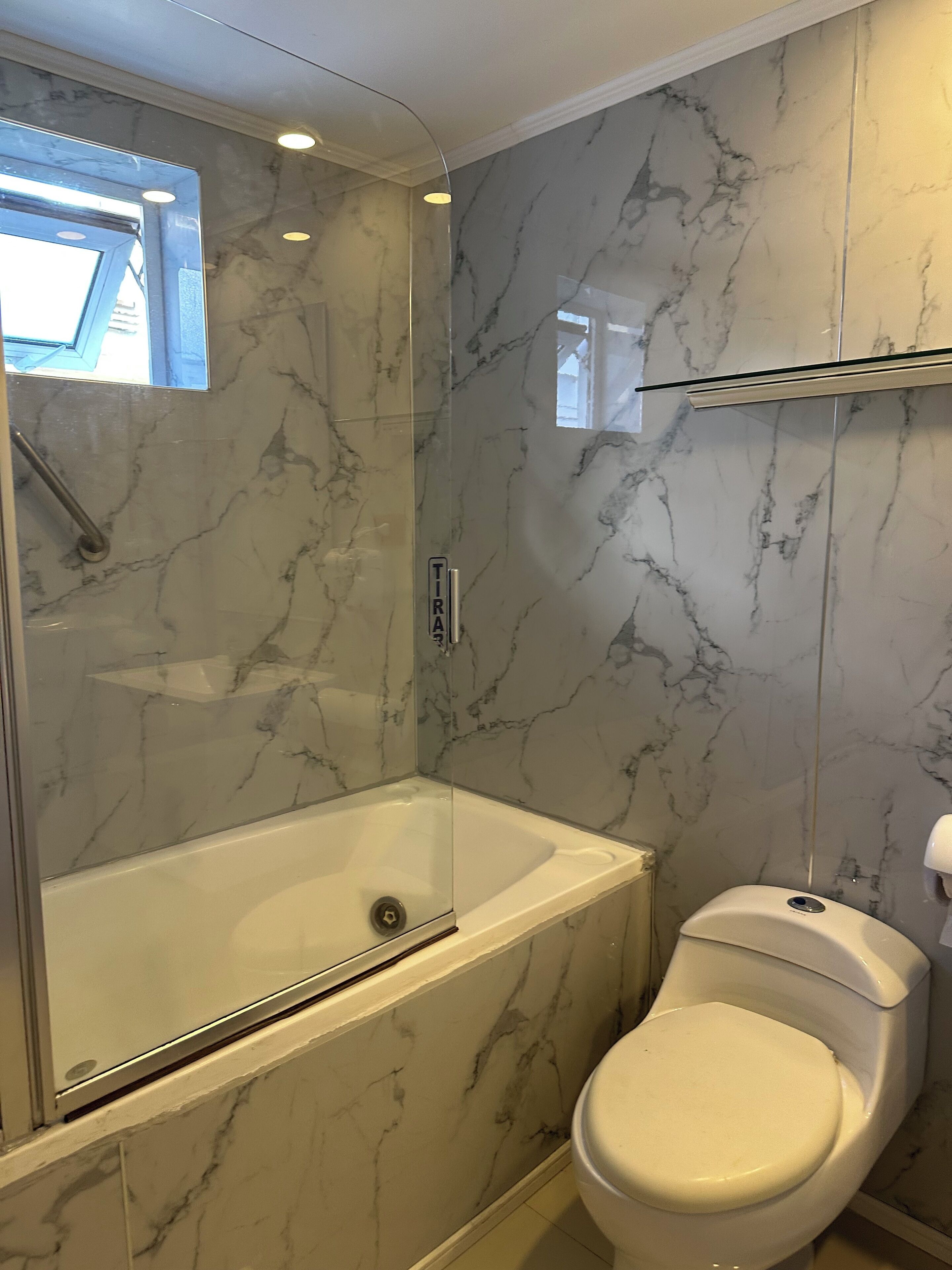 A bathroom with a glass-enclosed shower, a white bathtub, and a toilet.
