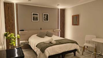 Un dormitorio moderno con cama, mesita de noche, silla y una obra de arte en la pared.