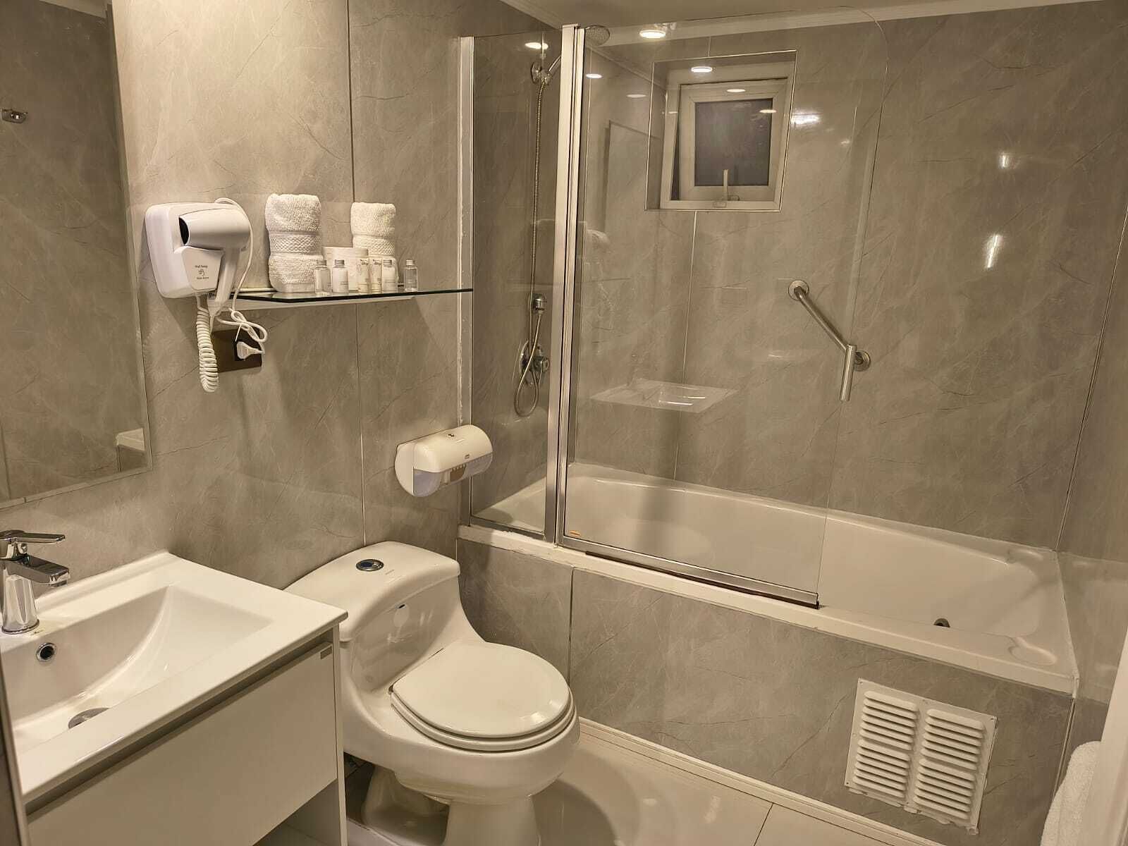 Un baño con inodoro, lavabo y ducha.