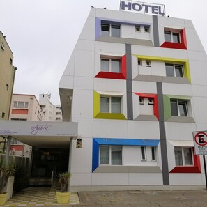 Un hotel de varios pisos con diseño moderno, que destaca un cartel grande con la palabra 'HOTEL' en la parte superior.