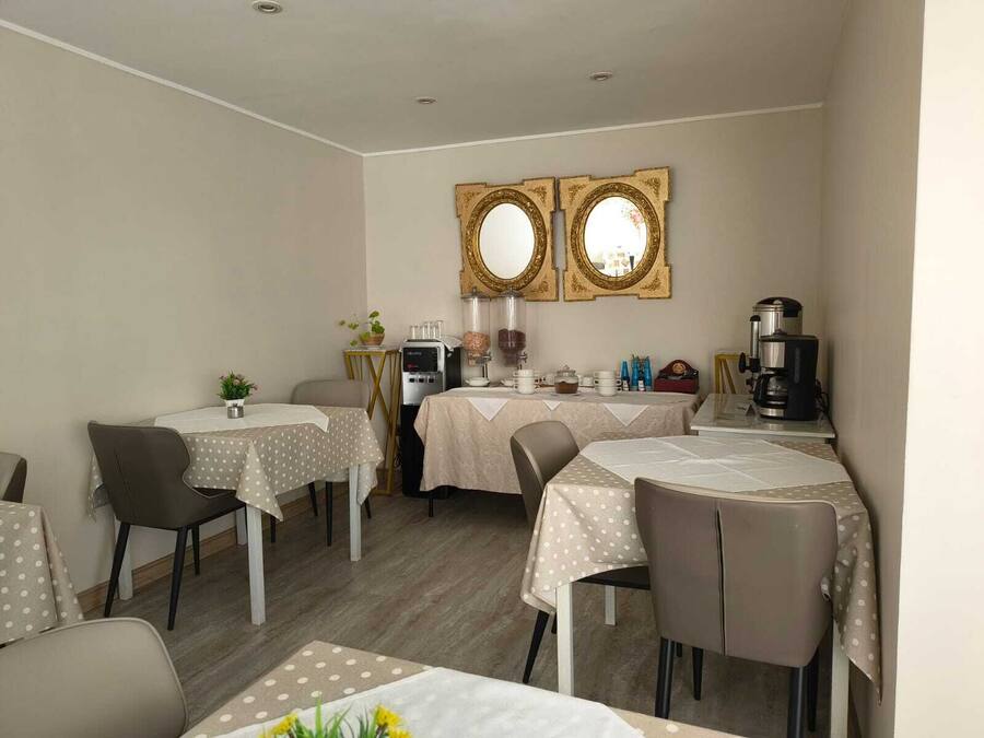 Un comedor con mesas, sillas, una cafetera y un espejo decorativo.