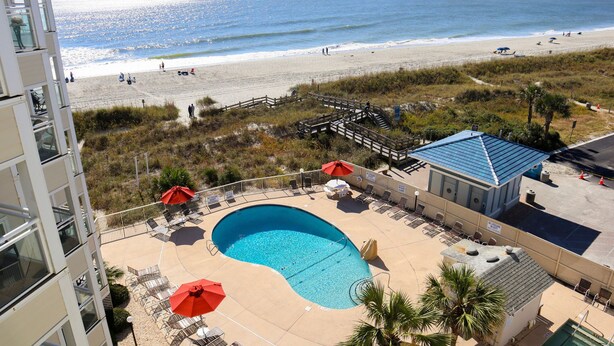 A hotel with a pool, beach view, and outdoor seating area. - 2-BR Beachfront Condo with Balcony Views! (North Myrtle Beach)