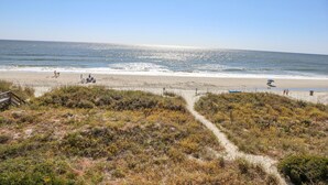 A beach with a clear sky, sandy shore, and a path leading to the water.