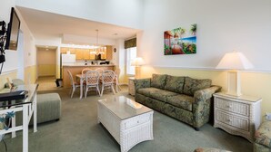 A living room with a sofa, a coffee table, and a dining area with chairs and a table.
