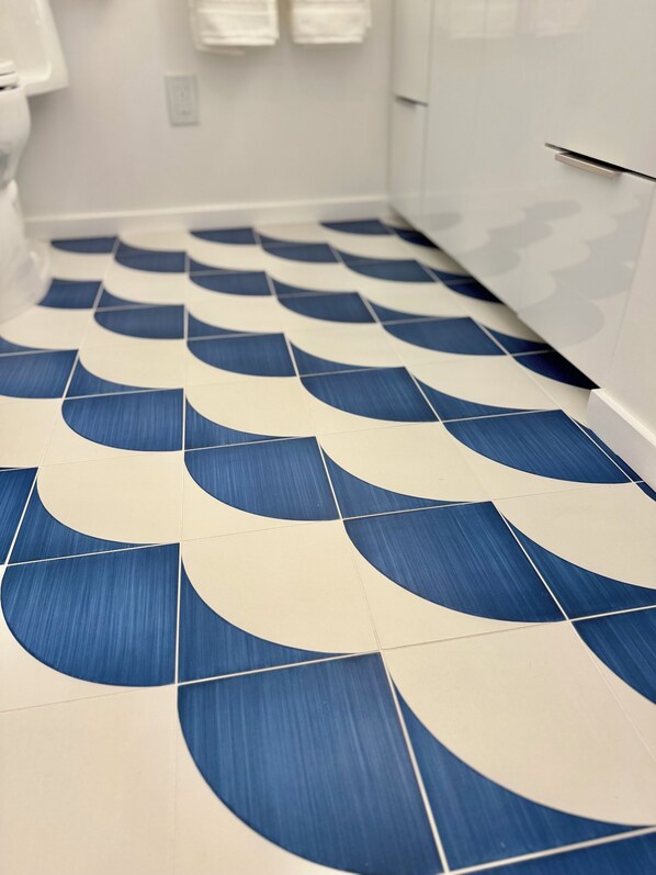 A bathroom with a tiled floor featuring a blue and white wave pattern.