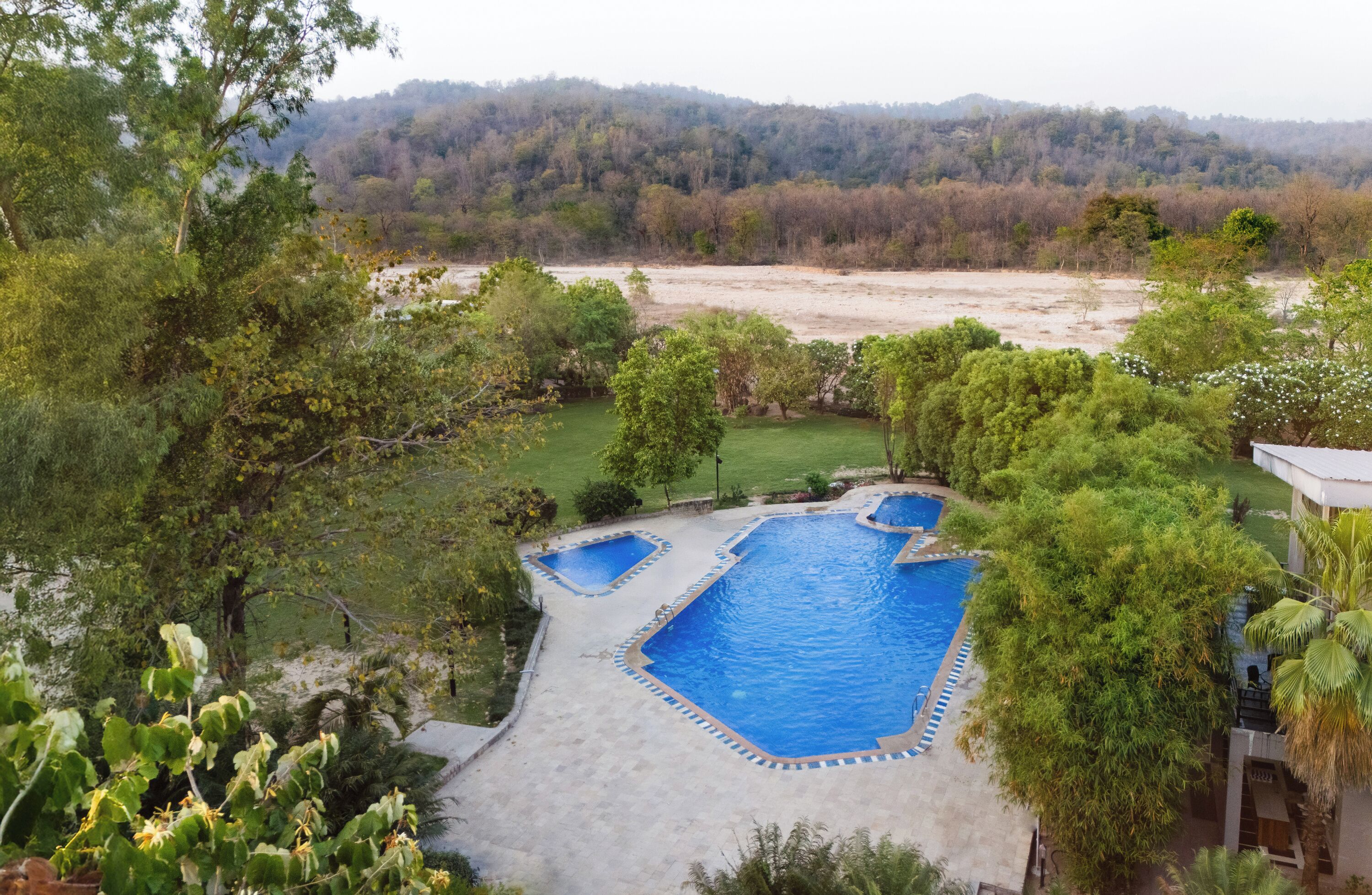 A swimming pool with a surrounding deck, surrounded by trees and a view of a forested area.