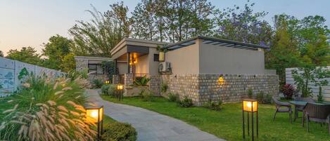 Una casa moderna con fachada de piedra, entrada pavimentada y mobiliario de exterior.