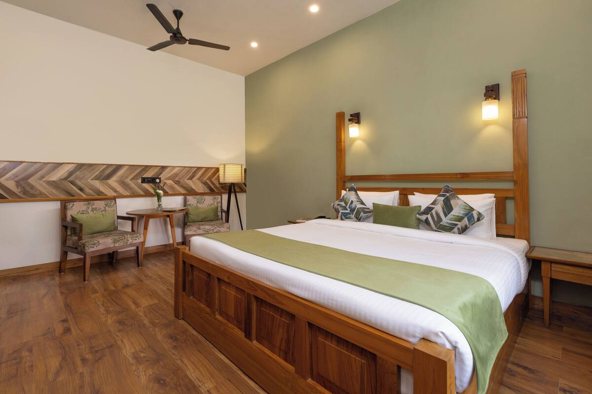 A bedroom with a wooden bed, a ceiling fan, a nightstand, a chair, and a lamp.