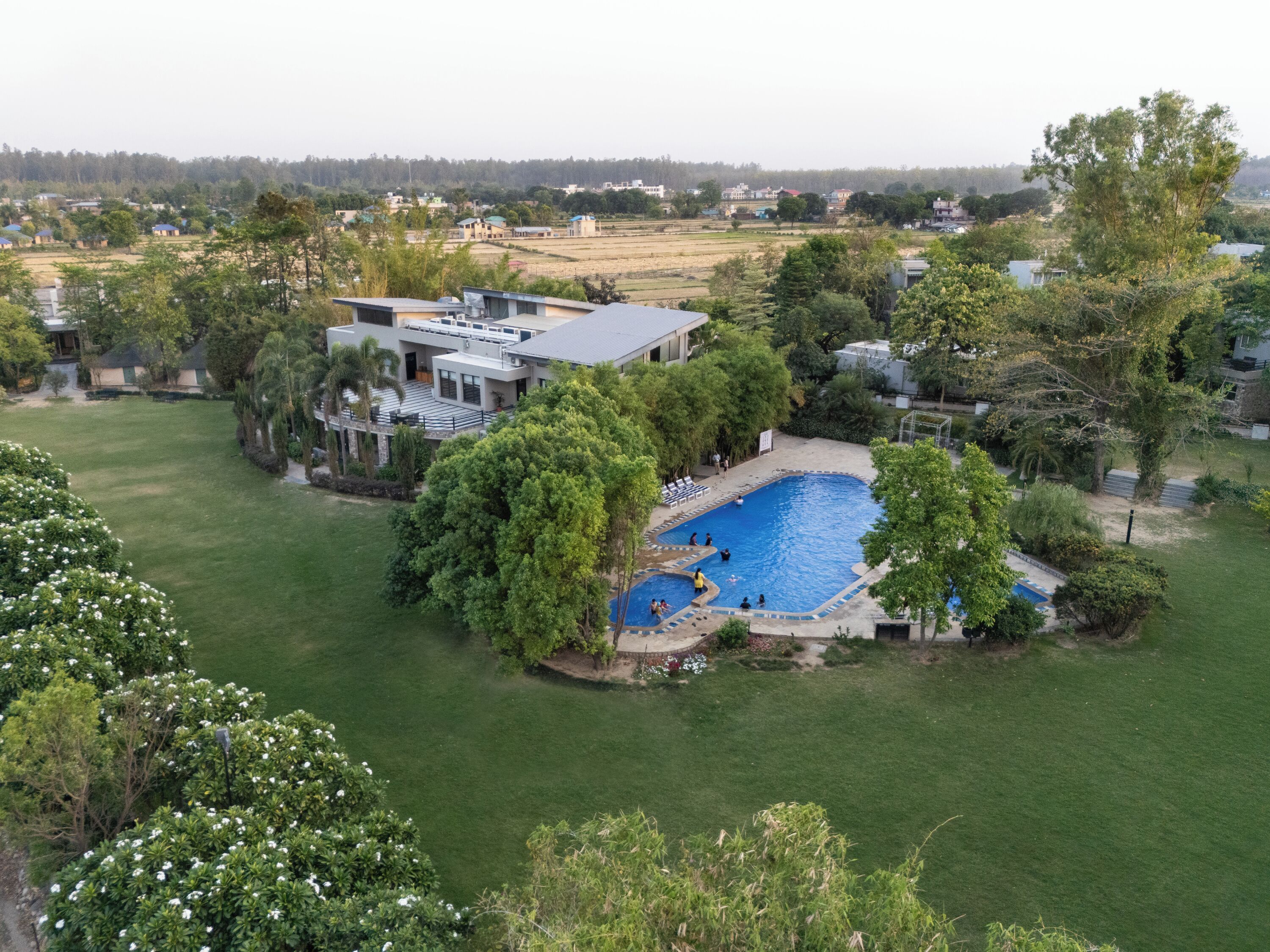 A residential property with a swimming pool, a large lawn, and a view of the surrounding area.