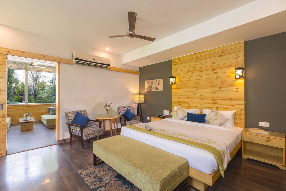 A bedroom with a bed, a chair, a small table, and a nightstand.