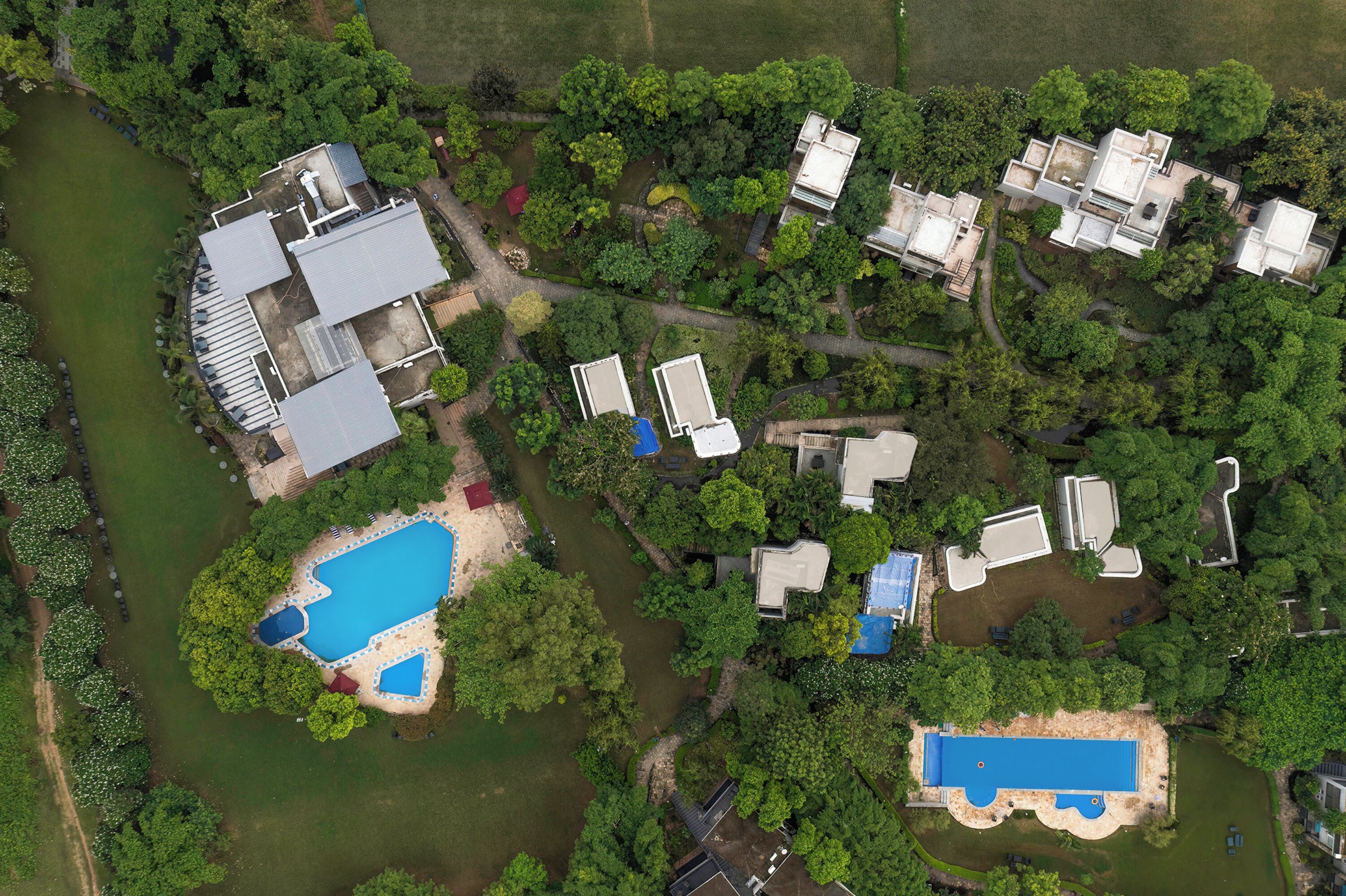 Vista aérea de una zona residencial con varias casas, una piscina y un pequeño cuerpo de agua.