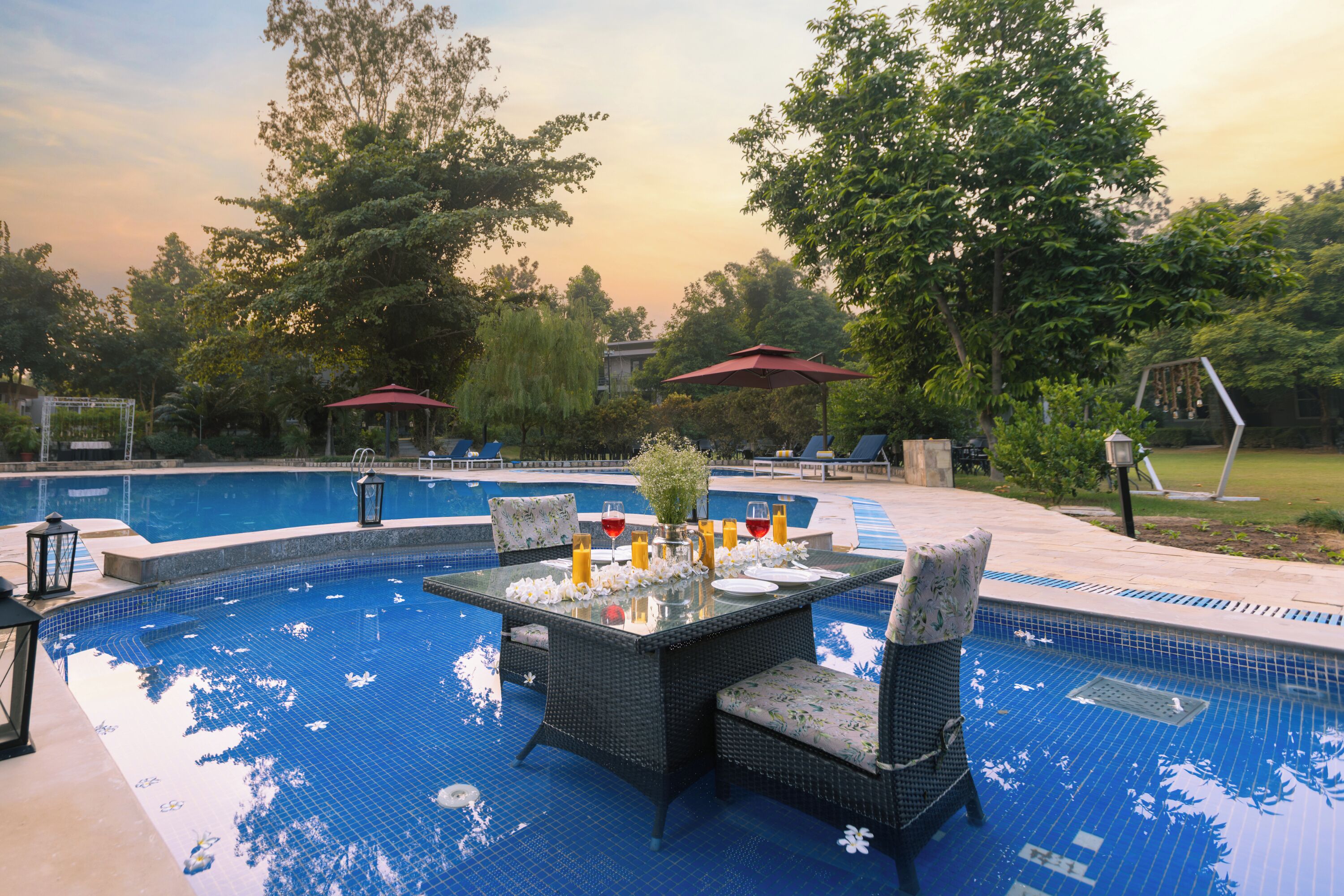 Zona de piscina con mesa de vidrio, sillas y un paraguas rojo.