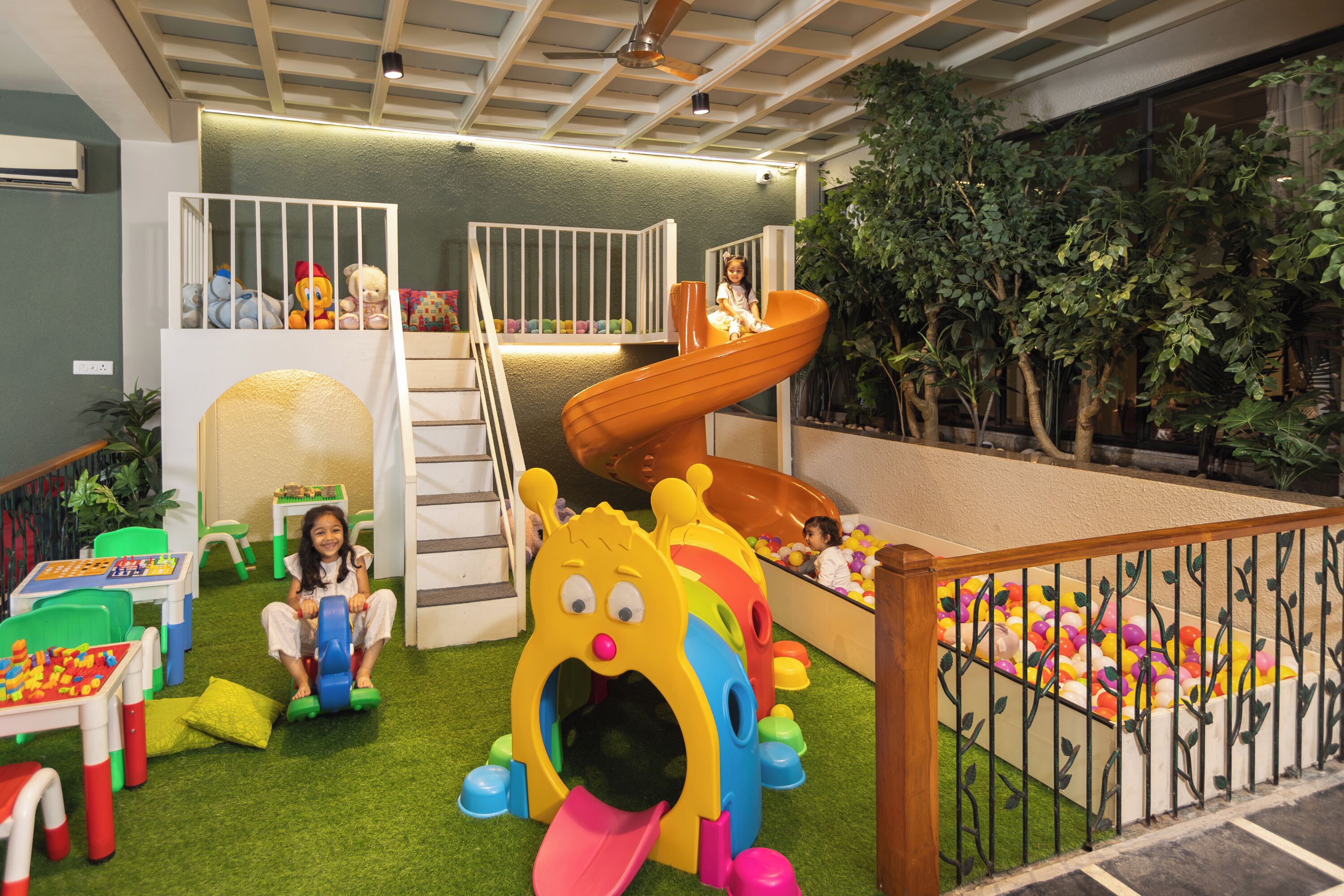 Un espace de jeux pour enfants avec un toboggan, un mur d’escalade et divers jouets.