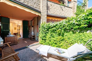 A courtyard with a wooden bench, a table with a magazine, and a chair. - Sea And Garden, Sestri Levante, Italy (Sestri Levante)