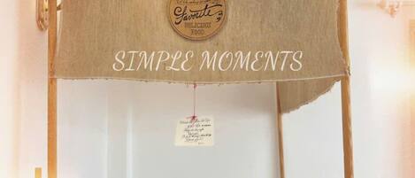 Una cocina con decoración rústica, que incluye un letrero colgante que dice "Simple Moments" y una pequeña mesa con electrodomésticos.