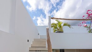 A modern staircase leading to a flat-roofed area with a view of the sky and a wooden beam. - Enaya Villa by Betterplace (Canggu)