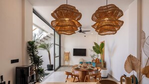 A modern dining area with wicker pendant lights, a round table set for four, and a large potted plant. - Enaya Villa by Betterplace (Canggu)