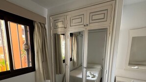 A bedroom with a bed, a wardrobe with mirrors, a desk, and a window with curtains.