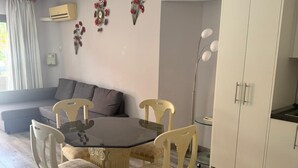 A modern living room with a dining table, two chairs, a sofa, and a cabinet.