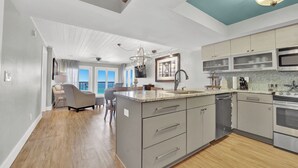 A modern kitchen with a central island, stainless steel appliances, and a view to the outside.