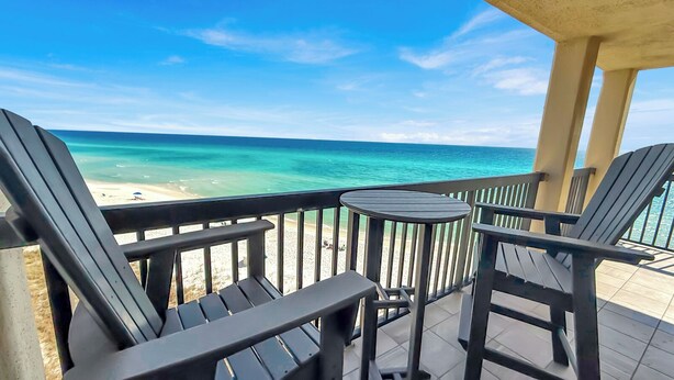 A balcony with a view of the beach and ocean.