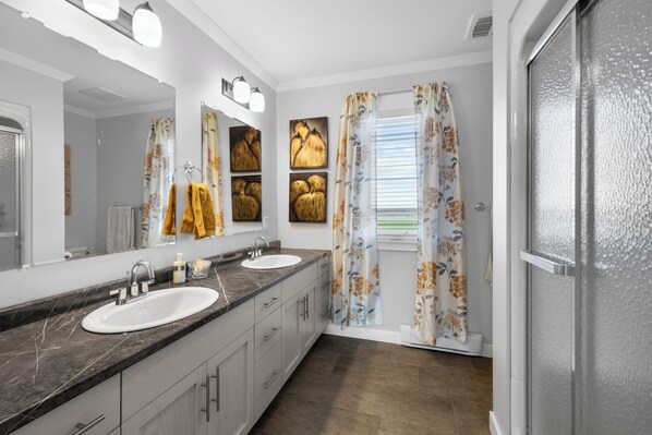 A modern bathroom with two sinks, a large mirror, and a shower area. - Large PEI Home with Bunk Room, Two Kitchens & Relaxing Outdoor Deck (Prince Edward Island)