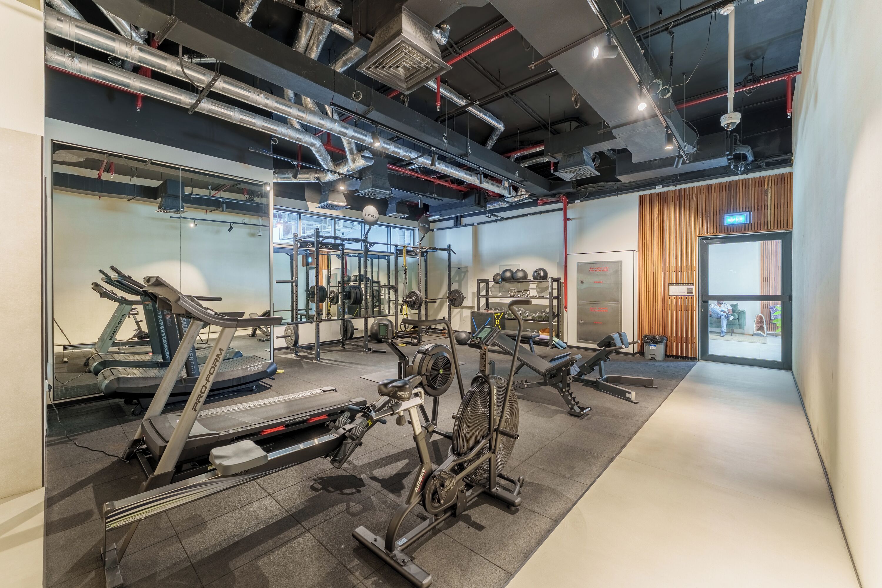 A gym with exercise equipment, a mirrored wall, and a large window.