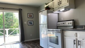 A kitchen with a refrigerator, oven, and stove. There are two framed pictures on the wall. - Cozy Family Getaway • Pet Friendly • Sleeps 8 • Near RRG • Campton, KY  (Campton)