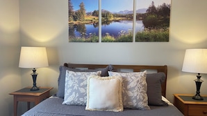 A bed with a grey quilt, two nightstands with lamps, and three landscape paintings on the wall. - Cozy Family Getaway • Pet Friendly • Sleeps 8 • Near RRG • Campton, KY  (Campton)