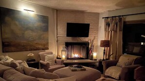 Una sala de estar acogedora con chimenea, asientos cómodos y un televisor de pantalla plana.